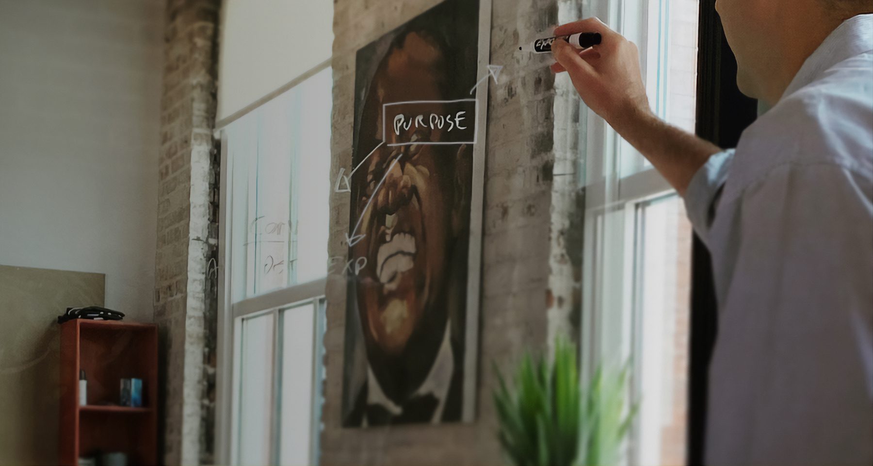 man brainstorming and writing on glass with whiteboard marker